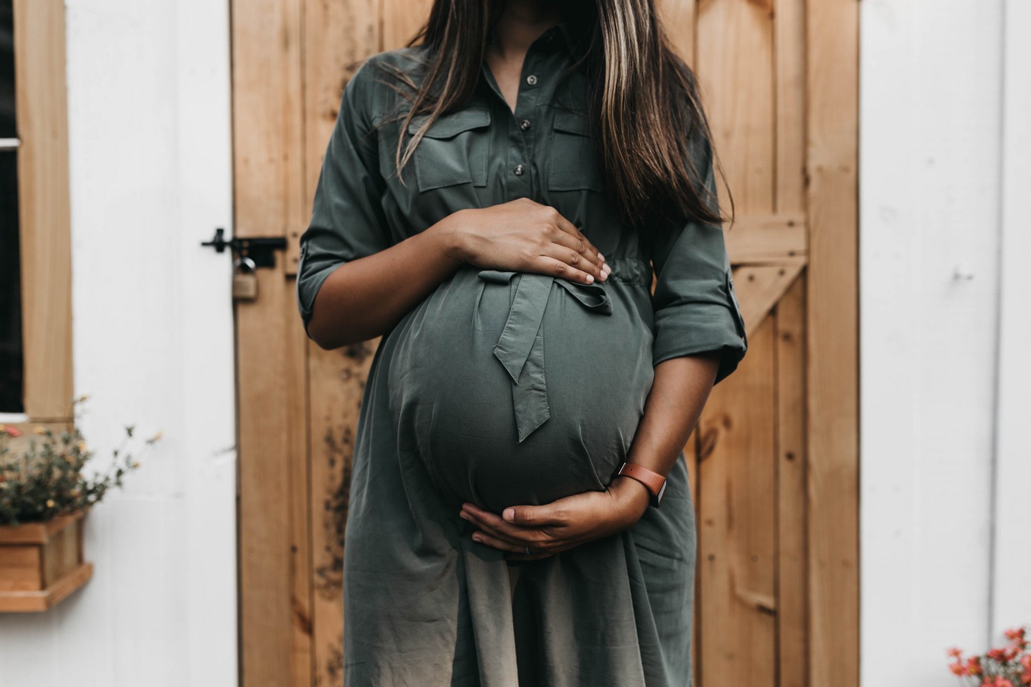 Pregnant woman holding her baby bump facing the camera